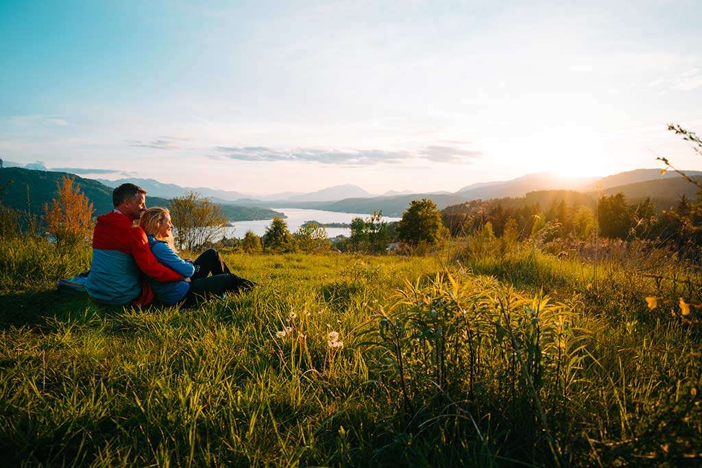 Pärchen sitzt in der Wiese mit Blick über Wörthersee